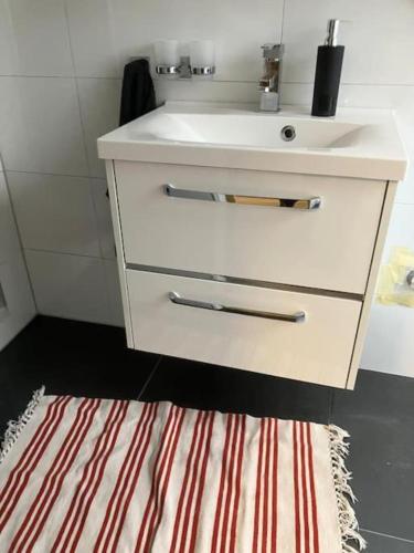 a bathroom with a white sink and a striped rug at Singel Apartment Wohnen auf Zeit in Hirschaid