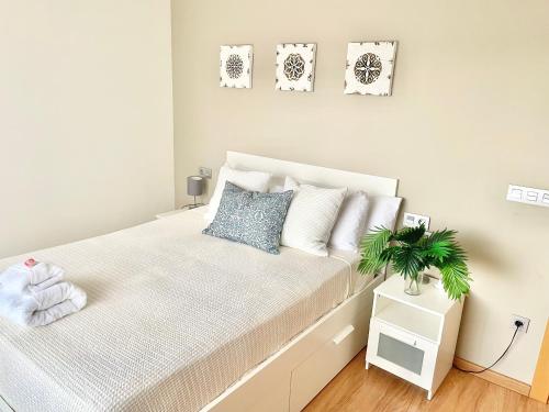 a bedroom with a white bed with a plant on it at Gijón Playa San Lorenzo Parking incluido in Gijón