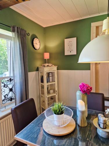 a dining room with a table with chairs and a clock at Ferienwohnung Hein sien Huus Rodenäs Nordfriesland in Rodenäs