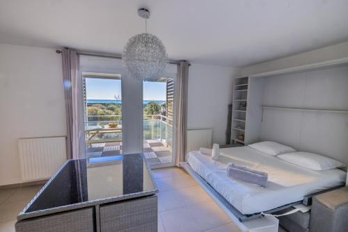 une chambre avec un lit et une grande fenêtre dans l'établissement appartement 1ère ligne avec parking et terrasse vue mer, à Palavas-les-Flots