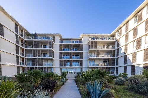 un immeuble d'appartements avec balcon et plantes dans l'établissement appartement 1ère ligne avec parking et terrasse vue mer, à Palavas-les-Flots