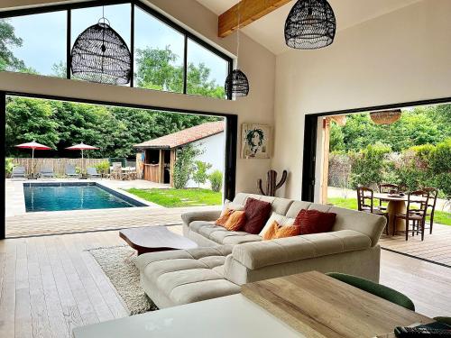 - un salon avec un canapé et une piscine dans l'établissement Villa Christelle, à Soustons