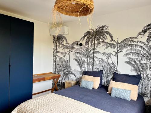 - une chambre avec un lit orné d'une fresque murale de palmiers dans l'établissement Villa Christelle, à Soustons
