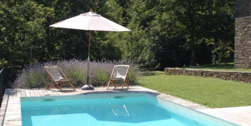 une piscine avec deux chaises et un parasol dans l'établissement La Bastide en Cévennes, à Saint-Hilaire-de-Lavit