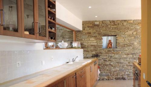 a kitchen with wooden cabinets and a stone wall at La Bastide en Cévennes in Saint-Hilaire-de-Lavit