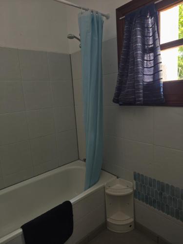 a bathroom with a bath tub with a blue shower curtain at Olive Branch El Chorro in El Chorro