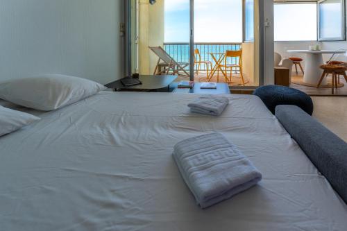 - un grand lit blanc avec 2 serviettes dans l'établissement 1ère ligne avenue saint maurice avec vue mer, à Palavas-les-Flots
