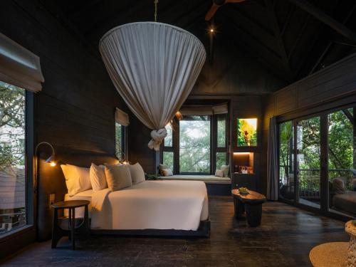 a bedroom with a bed and large windows at Oshom Bali at Nuanu Creative City in Canggu