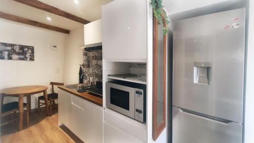 une cuisine avec un réfrigérateur en acier inoxydable et une table dans l'établissement Place DANTON SERIGNAN CENTRE, à Sérignan