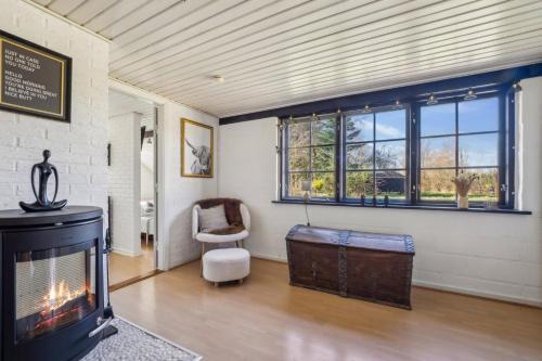 a living room with a fireplace and a chair at Astrup Vig Hideaway, Thatched Cottage with Shelter & Serenity in Roslev
