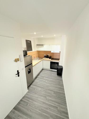 une petite cuisine avec des placards blancs et un couloir dans l'établissement Le Cocon de Clermont, à Clermont-lʼHérault