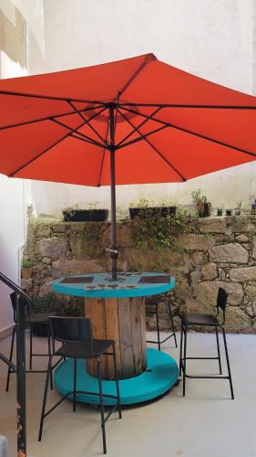 a table with a red umbrella and two chairs at House Pajarillo in Vigo