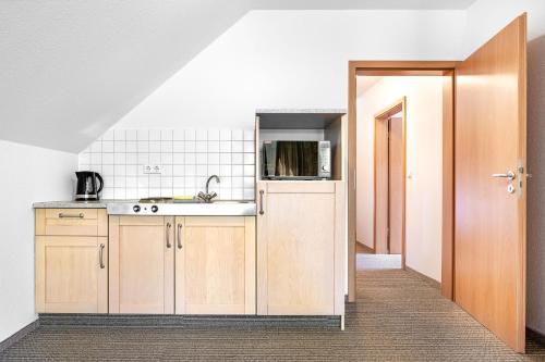 a kitchen with wooden cabinets and a sink at Hotel Heilemann in Wietmarschen