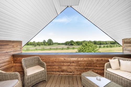 a screened porch with chairs and a large window at Hotel Heilemann in Wietmarschen