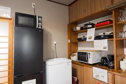 a kitchen with a black refrigerator and a microwave at 貸切御宿　憩（Ikoi）/ Nikko Kinugawa Area in Imaichi