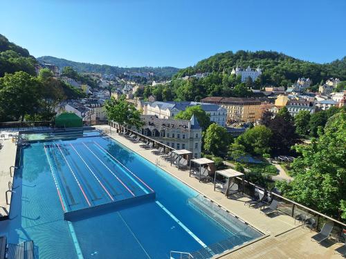 a large swimming pool with a city in the background at Vila Daniela in Karlovy Vary