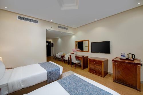 a hotel room with a bed and a desk and a television at Vendome Plaza Hotel in Dubai