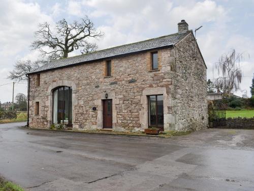 an old stone building sitting on the side of a street at Primrose Bank in Tirril