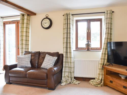 a living room with a leather couch and a television at Primrose Bank in Tirril