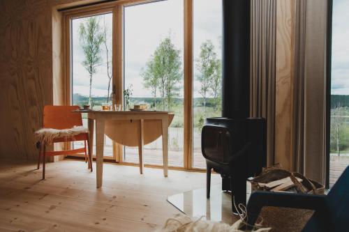 a living room with a table and a large window at Sukha Nordic Retreats in Arvika