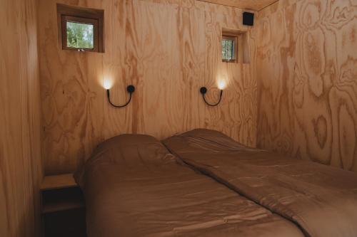a bed in a room with two lights on the wall at Sukha Nordic Retreats in Arvika