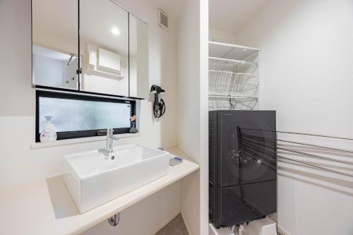 a white bathroom with a sink and a tv at First Choice in Tokyo