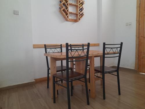 a wooden table with four chairs and a wine rack at Beskydy Holiday Rentals in Mbeya