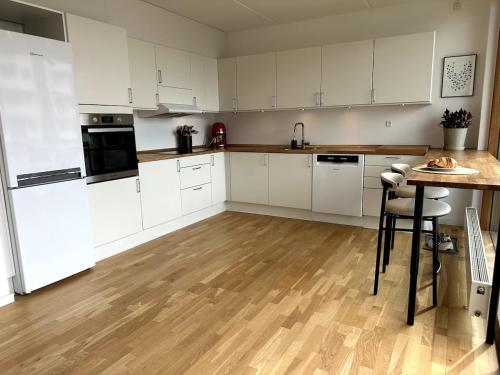 a kitchen with white cabinets and a wooden floor at On the beach, close to city centre & airport in Copenhagen