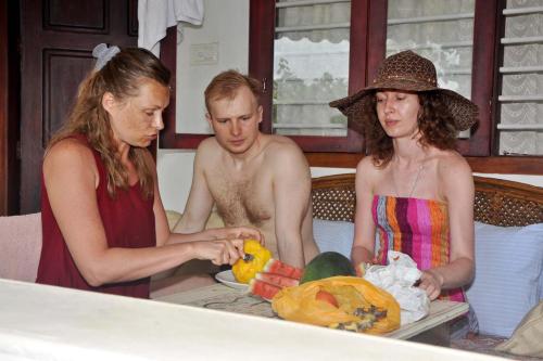 three people standing around a table with a plate of food at Angeo Beach House in Alleppey