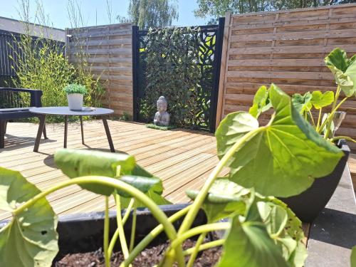 Una terraza en el patio trasero con una mesa y una cerca. en Le Ti'Cocoon Studio en Rez-de-Jardin, en Langueux