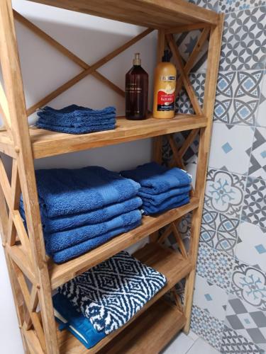 une étagère à serviettes dans une salle de bain avec des serviettes bleues dans l'établissement La Maison de Nini, à Andernos-les-Bains