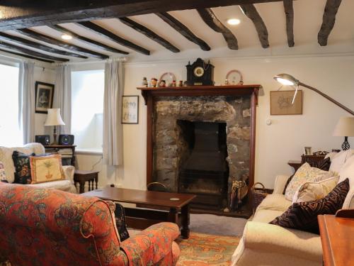 a living room with a fireplace with couches and a table at Bryn Hyfryd in Harlech