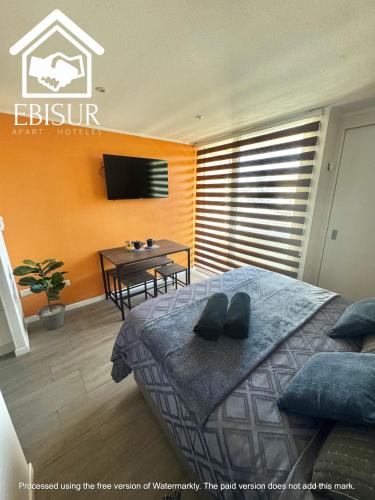 a bedroom with a bed and a table and a television at EBISUR Apart - Hoteles CRUZ in Concepción