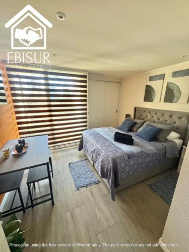 a bedroom with a bed and a table in it at EBISUR Apart - Hoteles CRUZ in Concepción