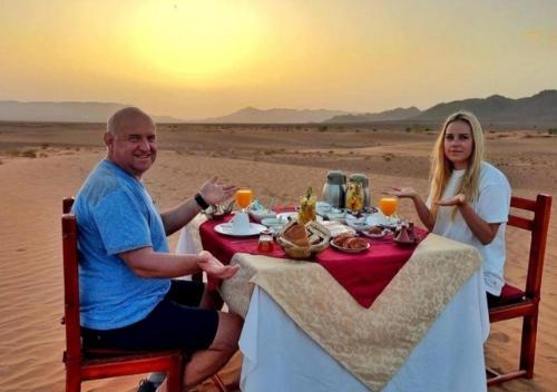 a man and woman sitting at a table in the desert at Sahara horizon Camp in Merzouga