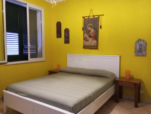 a bedroom with a bed and a yellow wall at Mami house in Sambuca di Sicilia