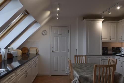 a kitchen with white cabinets and a table with a table cloth at Flat 18 Pochin House in St Austell