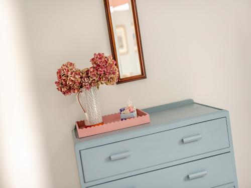 a dresser with a mirror and a vase with flowers on it at Hill View in Pateley Bridge