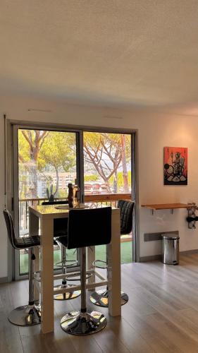 a room with a table and chairs and a large window at Résidence 3 rivières Studio haut de gamme au calme dans un parc de 8 hectares avec piscines in Mandelieu-la-Napoule