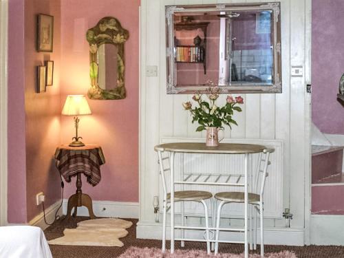 une pièce avec une table avec un vase de fleurs dessus dans l'établissement The Grooms Cottage-Uk45659, à Bishops Castle