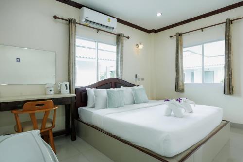 a bedroom with a white bed and a desk and two windows at Naris phu view resort in Ban Pan Cho