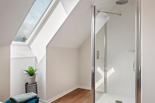 La salle de bains blanche est pourvue d'une douche en verre et d'une lucarne. dans l'établissement Maison rénovée haut de gamme - 4 chambres, terrasse, parking, à Montigny
