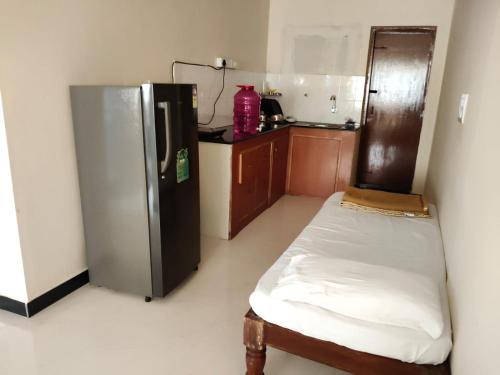 a kitchen with a refrigerator and a bed in a room at Nandan Suits in Mysore