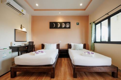 two beds in a room with a desk at Naris phu view resort in Ban Pan Cho