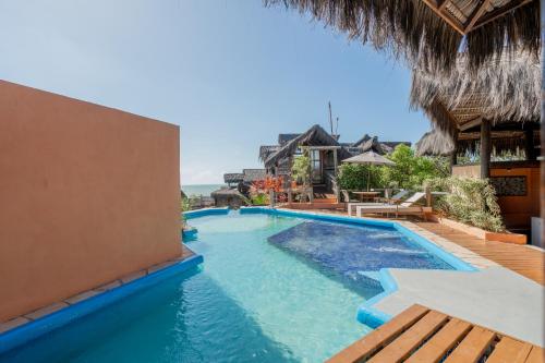 a swimming pool at a resort with a thatched roof at Dayo Hotel in Flecheiras