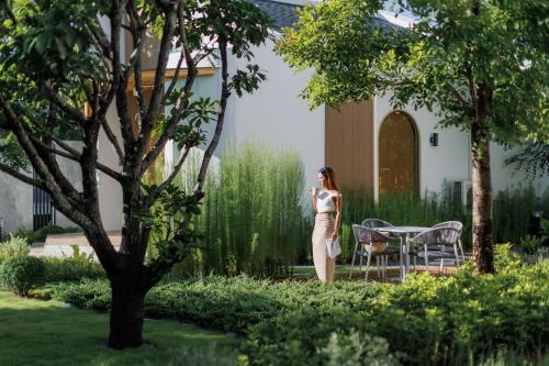 a woman standing in a garden talking on a cell phone at Naris phu view resort in Ban Pan Cho