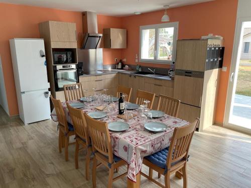 une salle à manger avec une table et des chaises et une cuisine dans l'établissement Maison neuve vue sur l'ancien moulin du Médoc, à Lesparre-Médoc