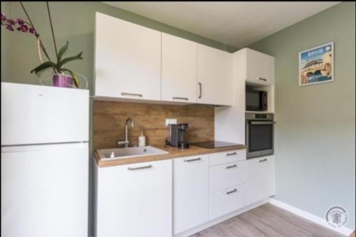 une cuisine avec des armoires blanches et un évier dans l'établissement Gold beach gîte, à Ver-sur-Mer