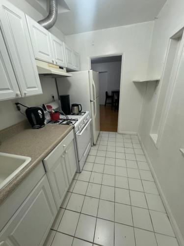 a kitchen with white cabinets and a white tiled floor at Females room bunk beds in Los Angeles