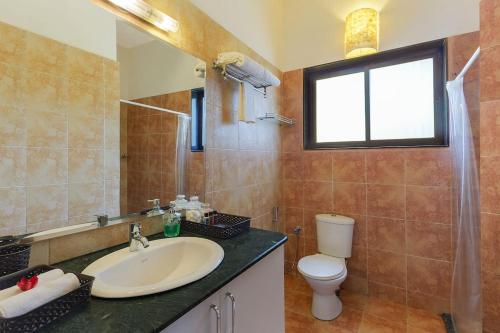 a bathroom with a sink and a toilet and a window at 5 Tropical Woods 4 BR VillaGoa Pool Cook in Bardez